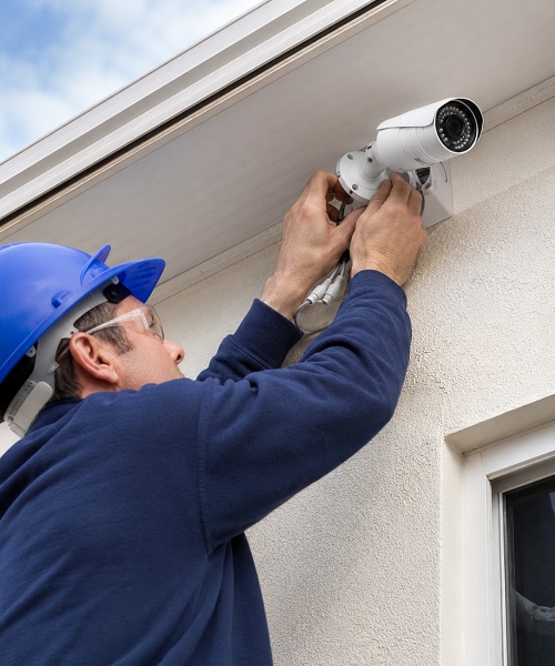 Technician installing outdoor bullet CCTV camera on home exterior in Dammam